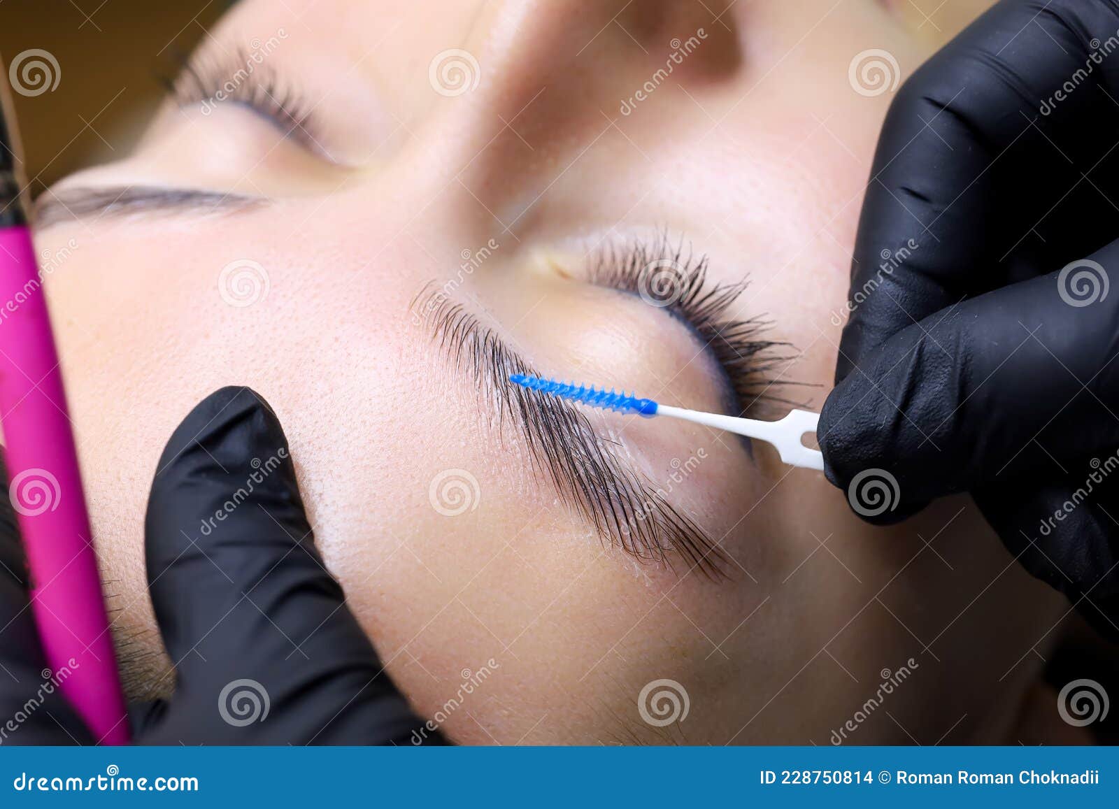 the master`s hands holding the brush the master directs the growth of hairs after lamination of the eyebrows