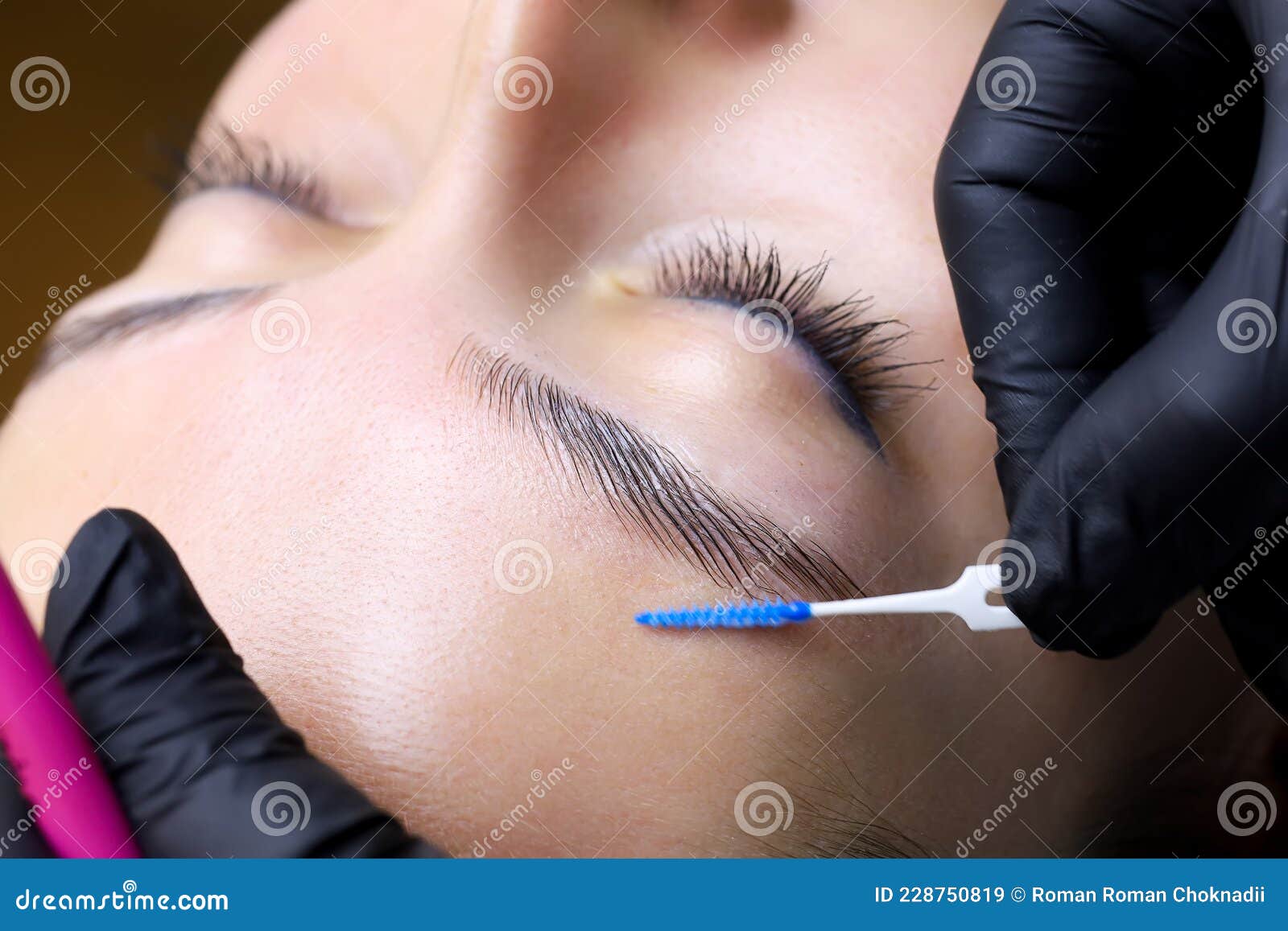 the master`s hands holding the brush the master directs the growth of hairs after lamination of the eyebrows
