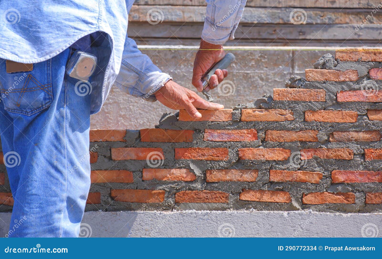 Close Up of Mature Builder Hands is Making Low Brick Fence Wall in