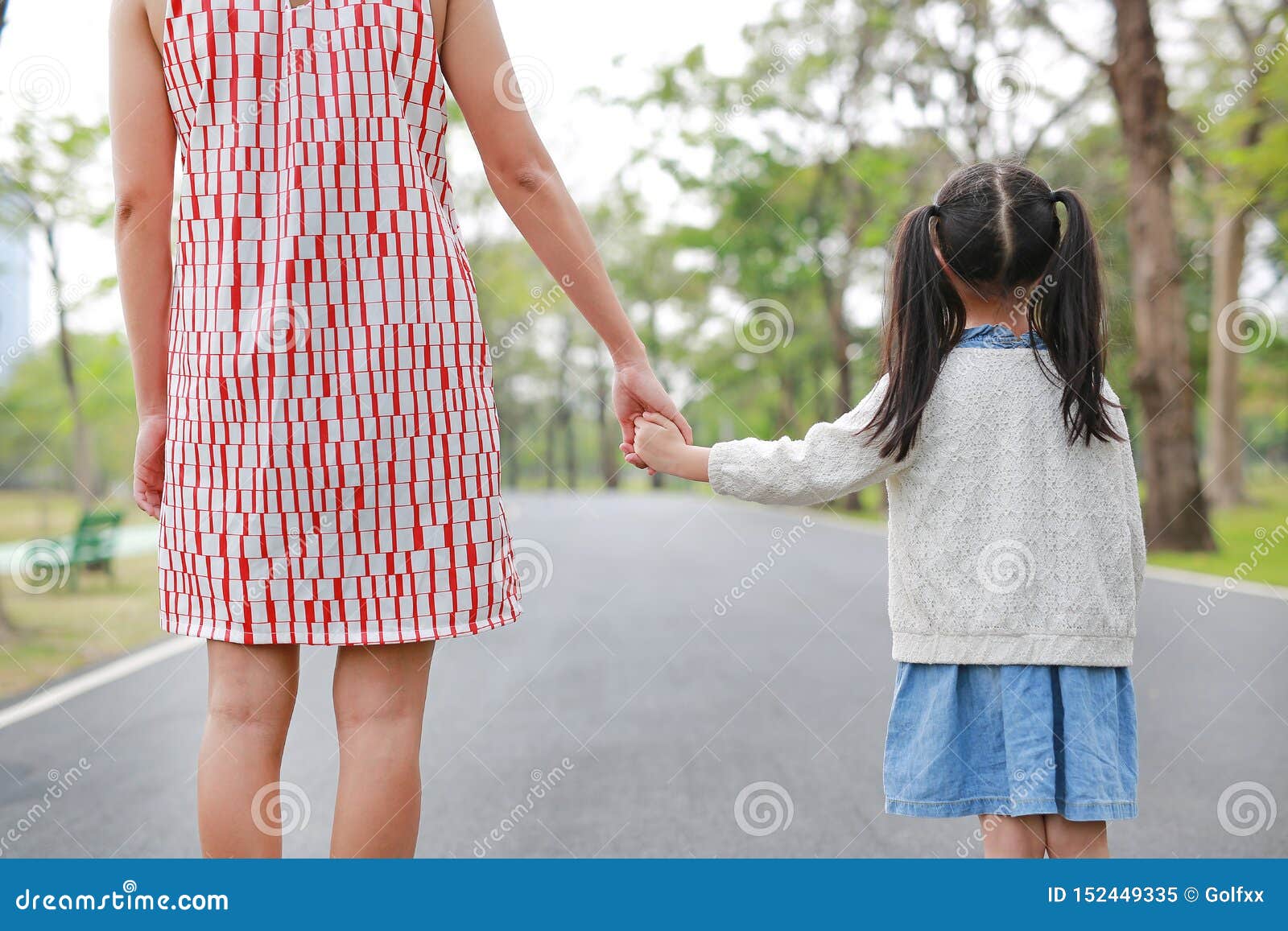 Daughter back. Mother and daughter back view. Mother and daughter hand. Mom hands up. Mom carrying daughter back view.