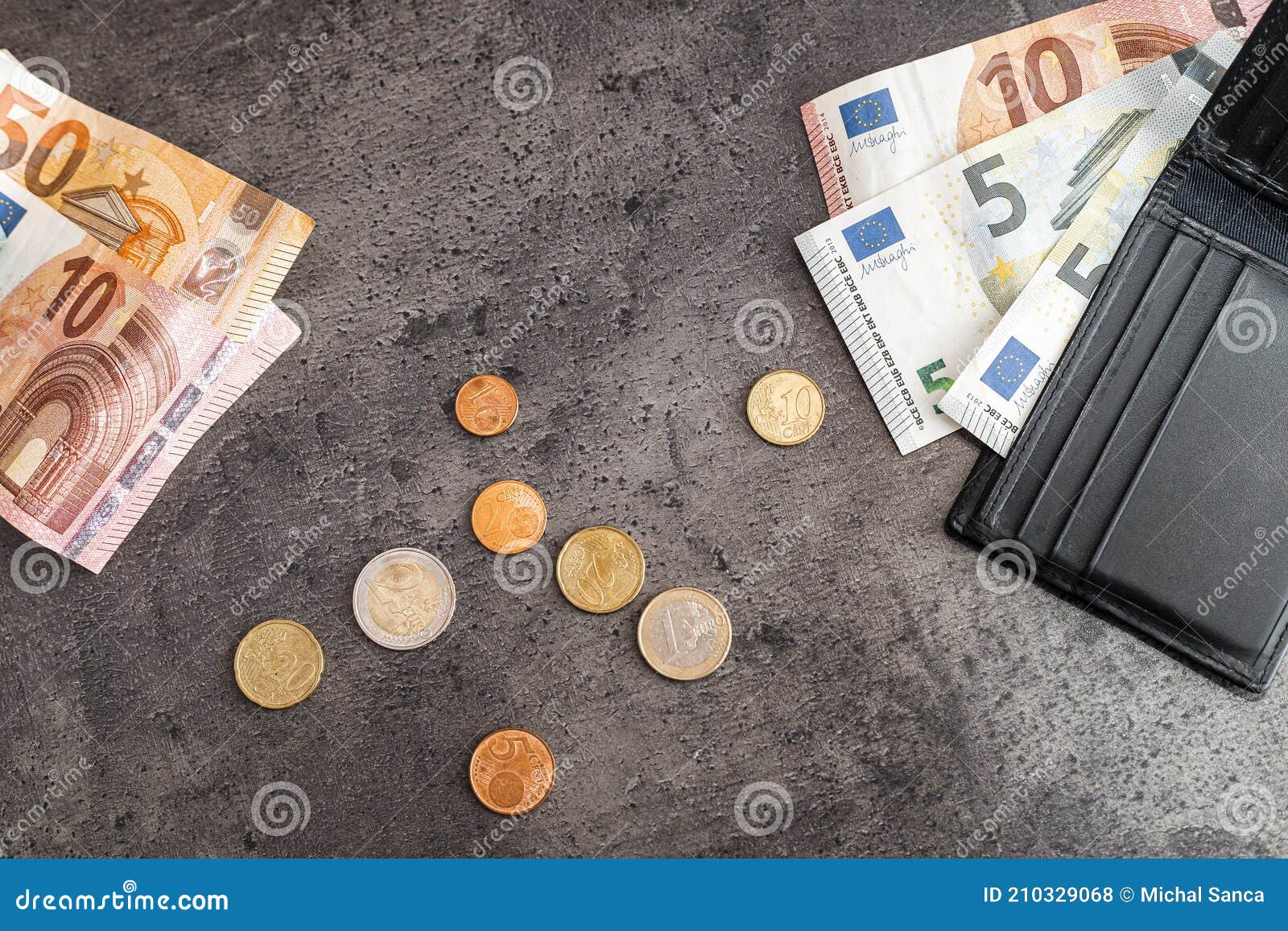 close up of money banknotes, coins and black wallet. euros on dark background