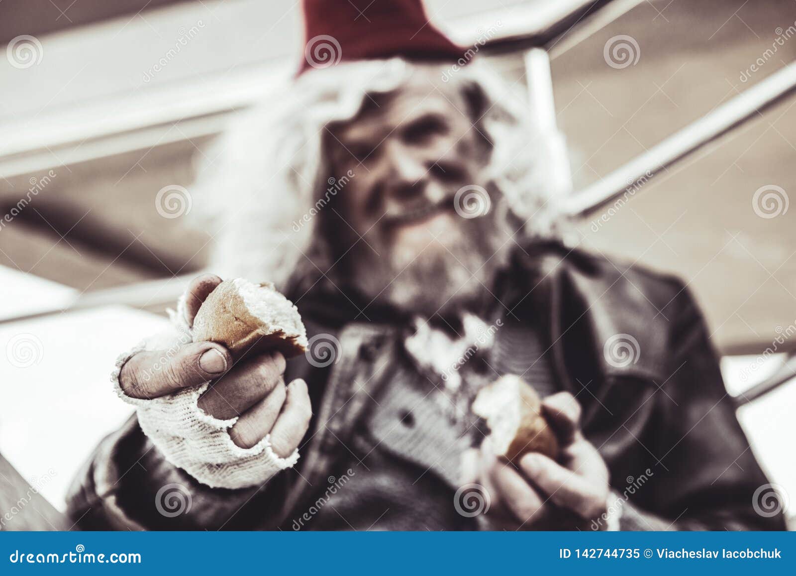 close up of old almsman whose holding pieces of baking and sharing it with photographer.