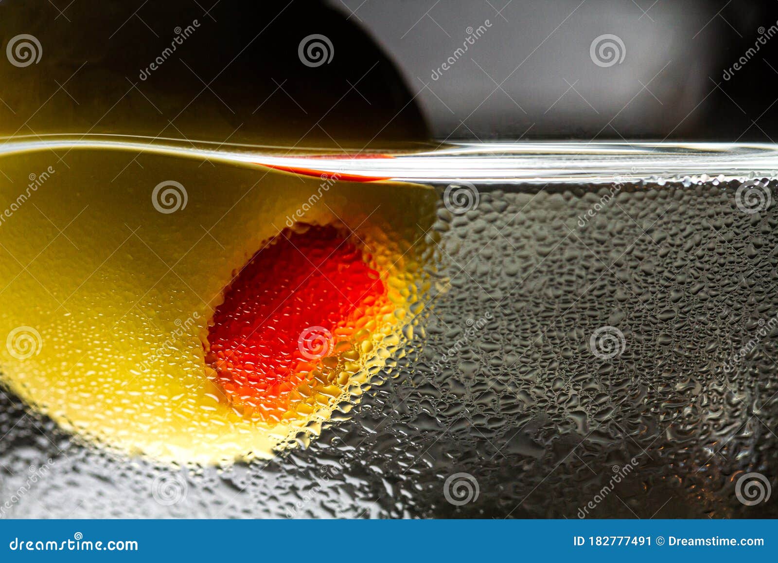 close-up of olive with pepper in a martini glass with drops