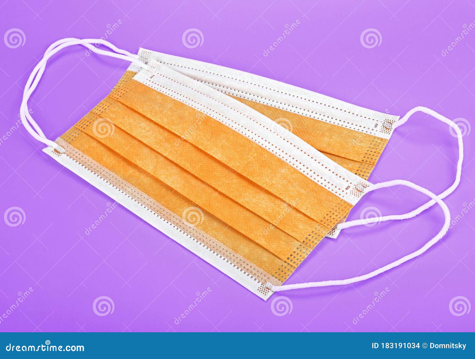 Close Up of Orange Disposable Face Masks on Violet Background. Protective Face Mask Stock Photo