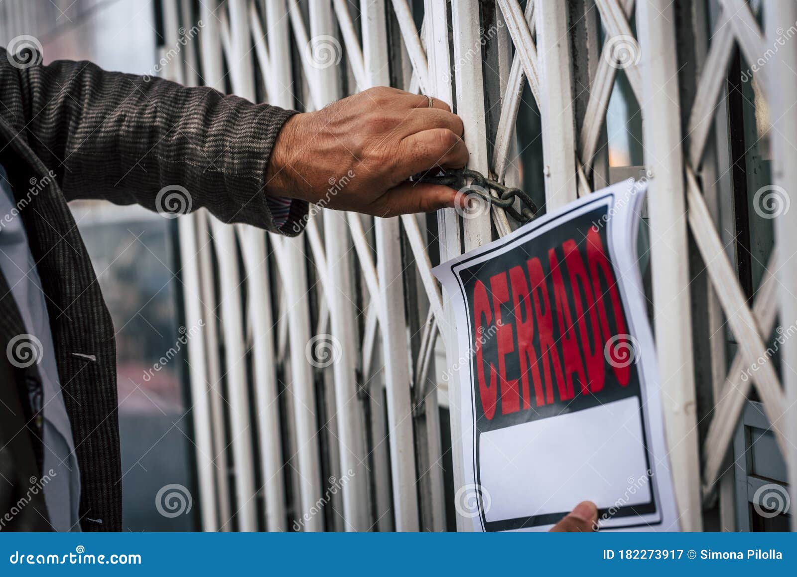 close up of owner man with closed sign out of his store shop - end of business economy concept - spanish words cerrado panel and