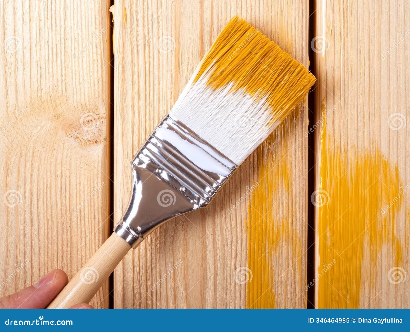 close-up of a paintbrush applying paint on wood, highlighting painting and renovation work.