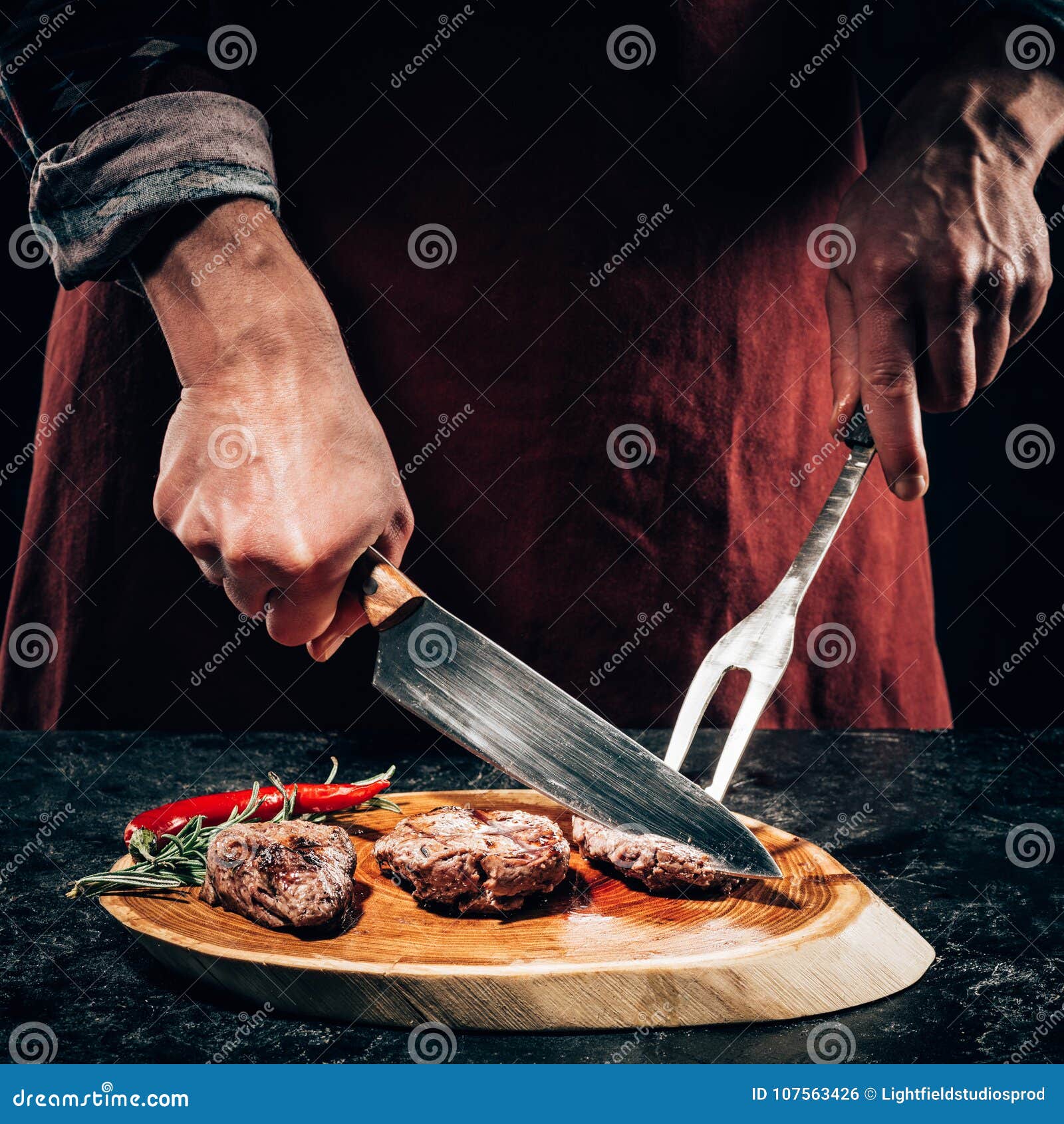 https://thumbs.dreamstime.com/z/close-up-partial-view-chef-apron-meat-fork-knife-slicing-gourmet-grilled-steaks-rosemary-chili-pepper-107563426.jpg