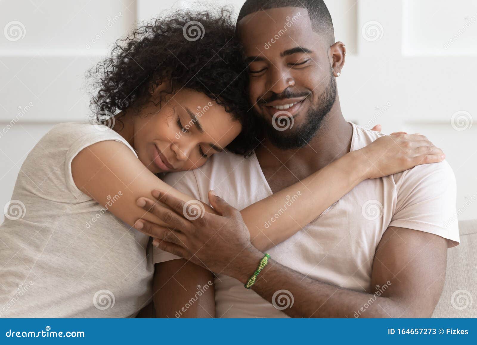 happy african american couple cuddle hugging at home