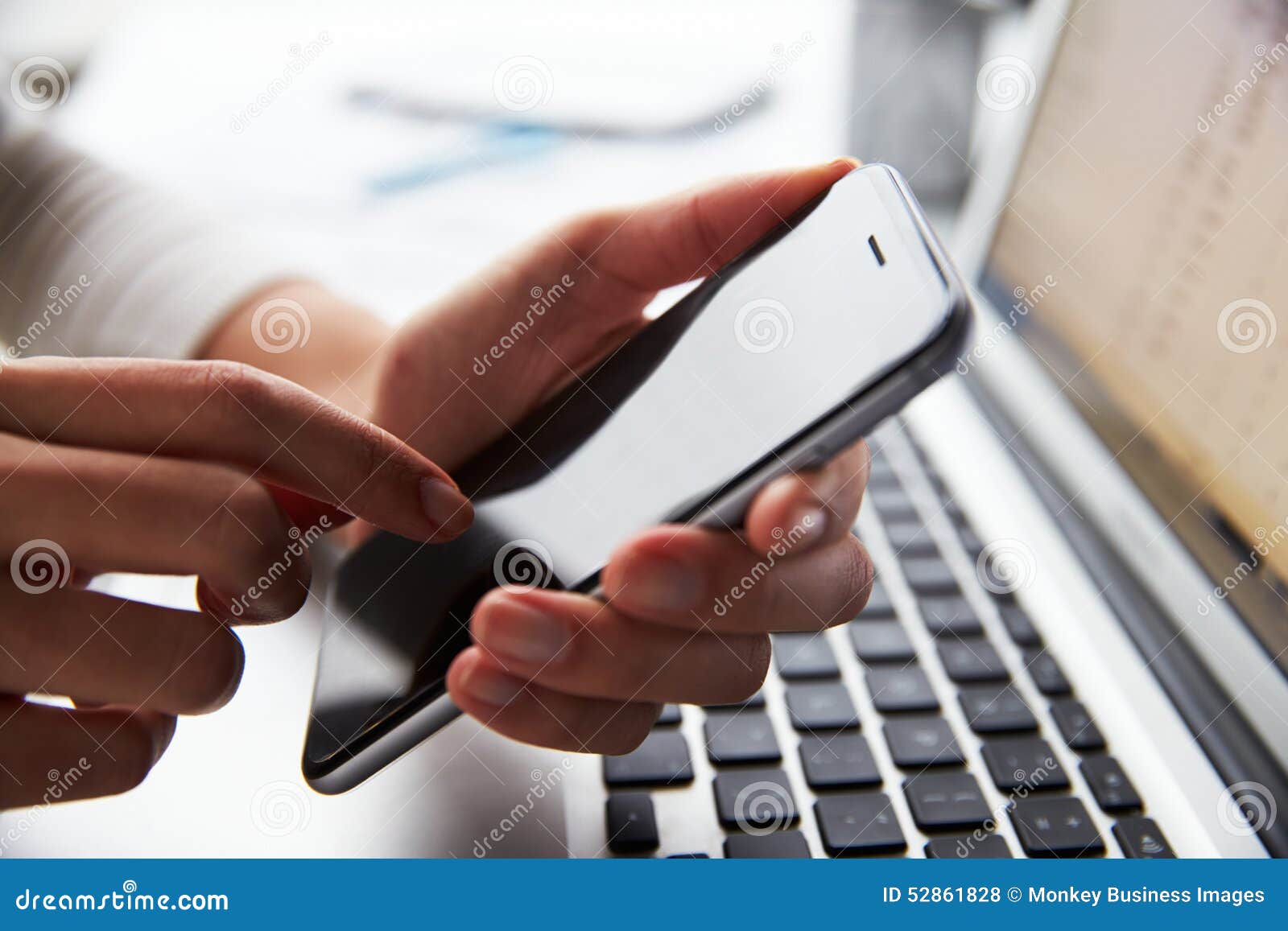 close up of person at laptop using mobile phone