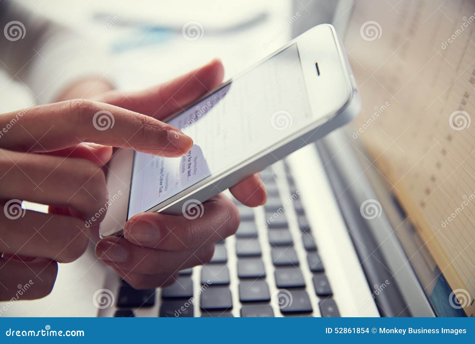 close up of person at laptop using mobile phone