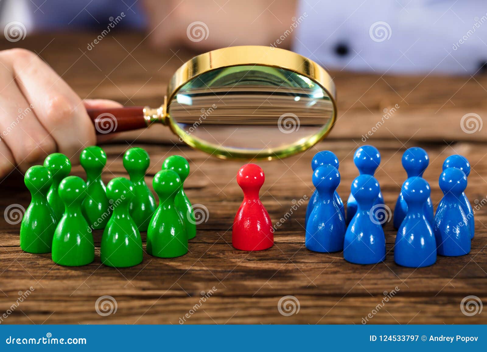  A person holding a magnifying glass over a table with green, red, and blue game pieces.
