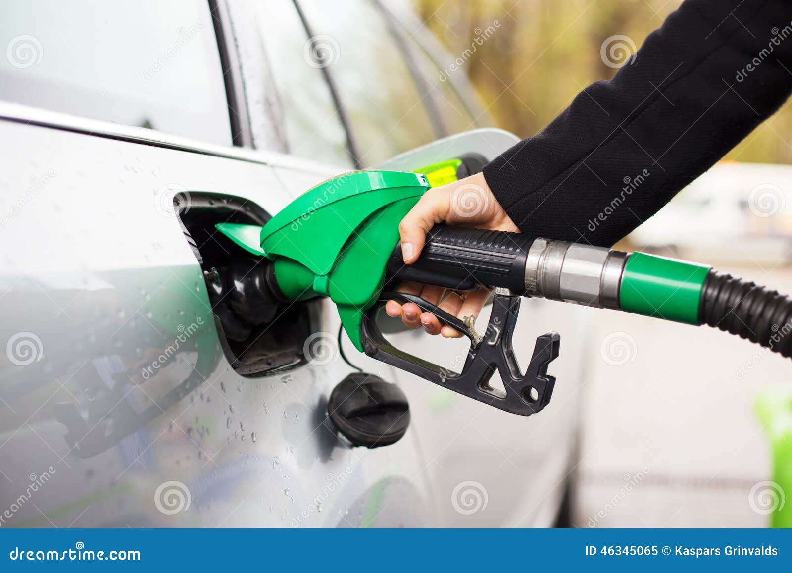 close-up photo of hand holding fuel pump and refilling car at petrol station