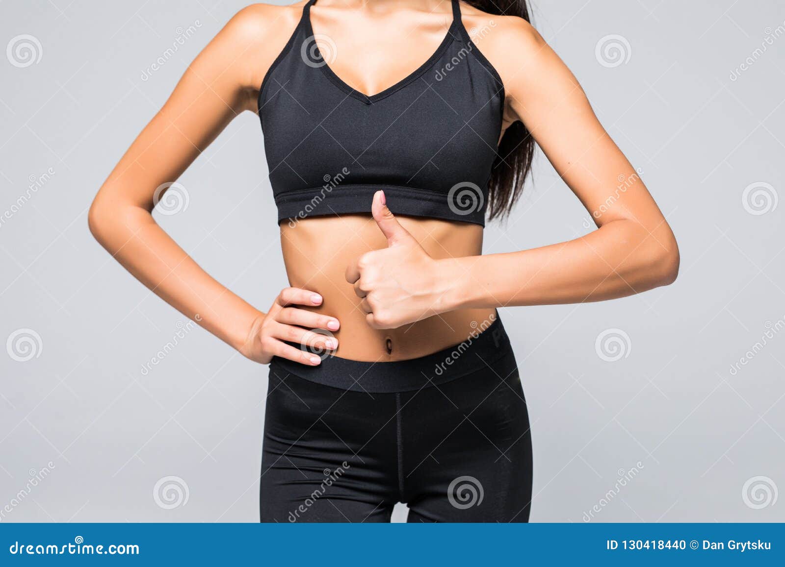 close up photo of perfect fit slim woman`s belly and thumb up on gray background