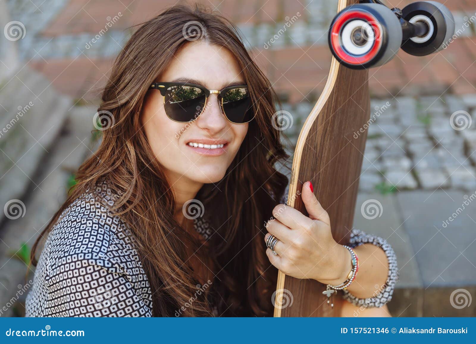 Close Up Portrait Of Beautiful Young Woman Sitting On The Ground And Holding A Longboard In The 