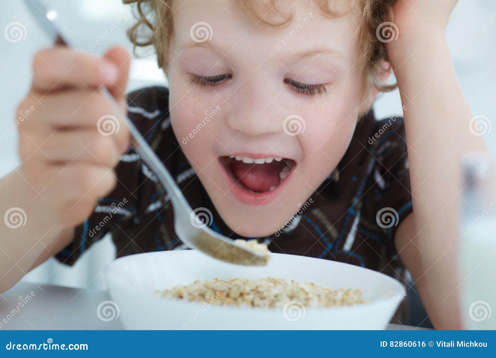 Close Up Portrait Of Boy Eating Cereal While Having Breakfast In The