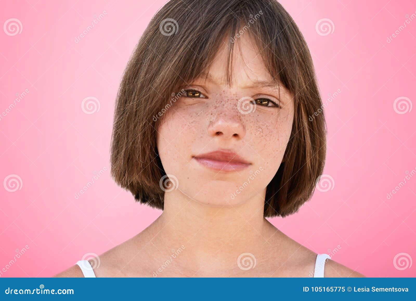 close up portrait of freckled stylish small kid looks with narrow dark eyes directly into camera, has serious expression, 