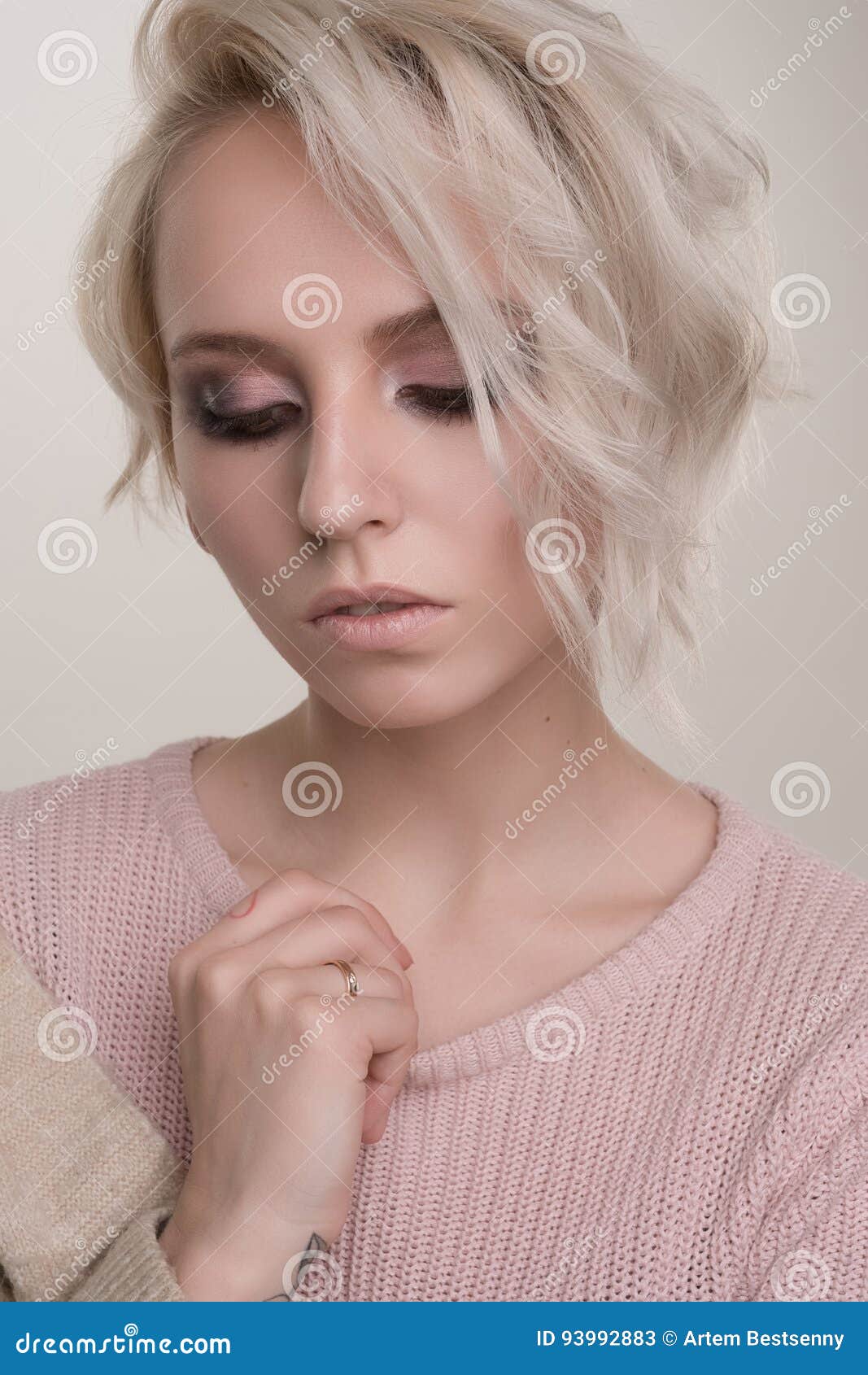 Close Up Portrait In A Half Turn Girls Blonde With Dark Eye Makeup And Short Hair In A Light Pink Sweater With A Hand On The Coll Stock Image Image Of Light