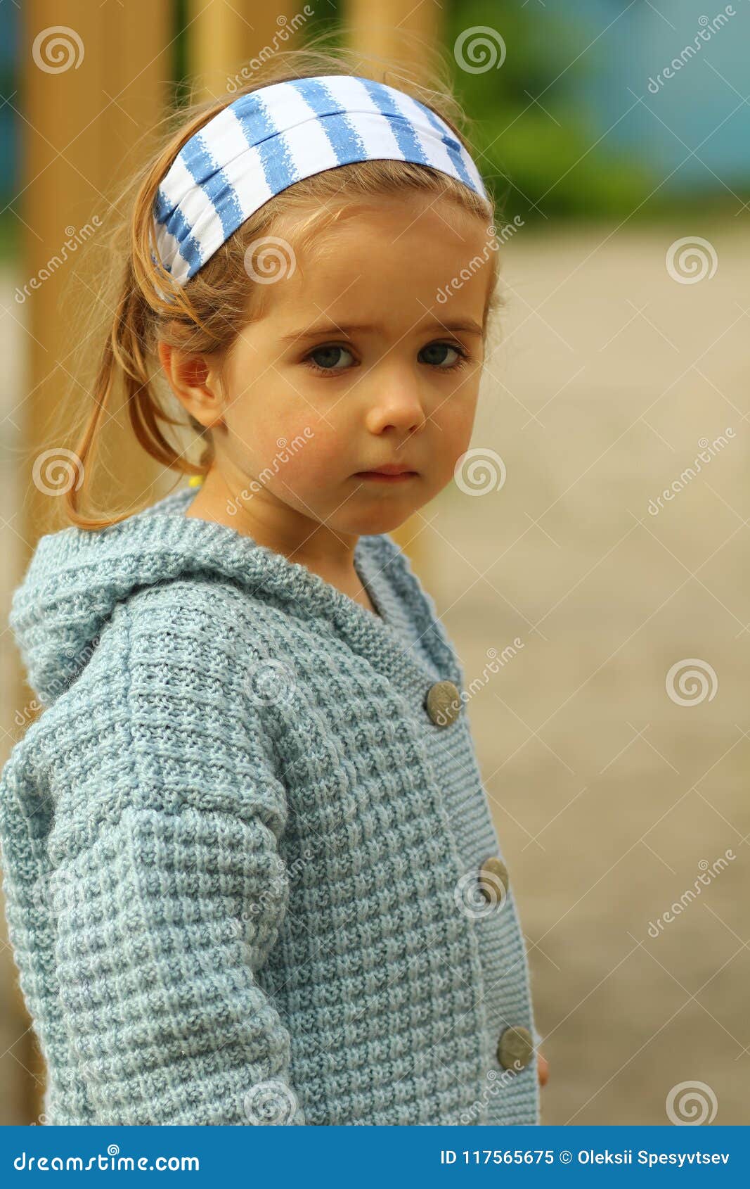 Close Up Portrait Of A Serious Toddler Girl In Blue Hand