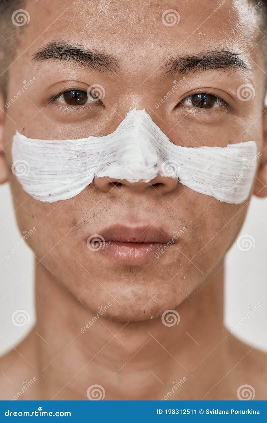 close up portrait of young asian man with problematic skin and hyperpigmentation applied mask on his face, looking at