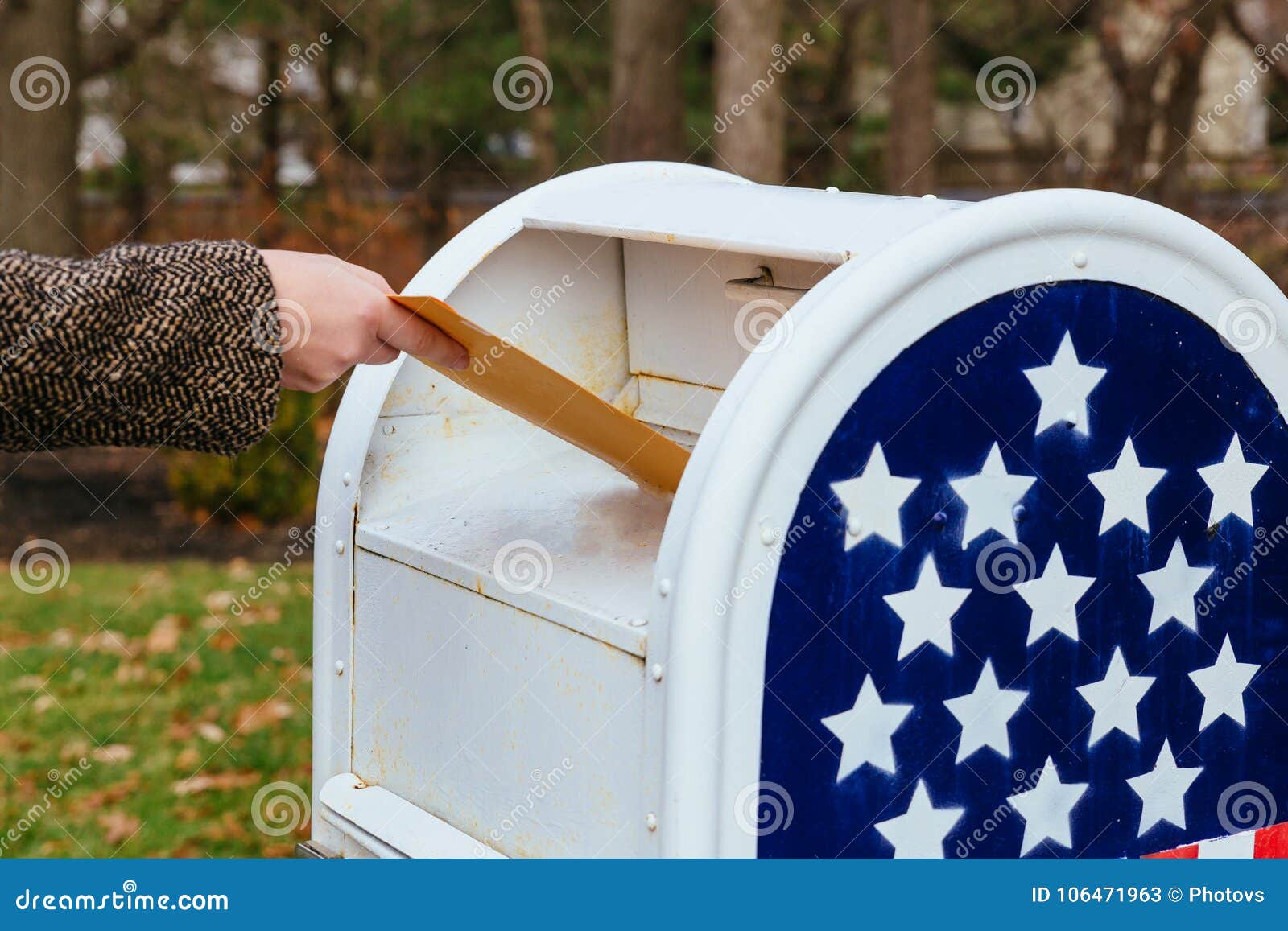 close-up of postman putting letters mailbox american flag