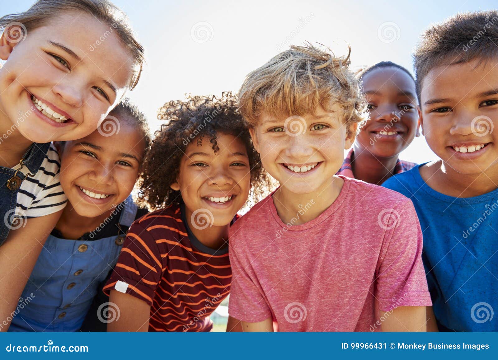 close up of pre-teen friends in a park smiling to camera