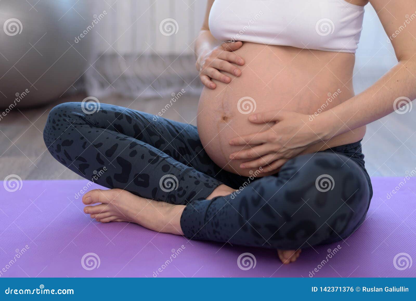 Close Up Of Pregnant Woman Sitting On The Floor Stock Photo