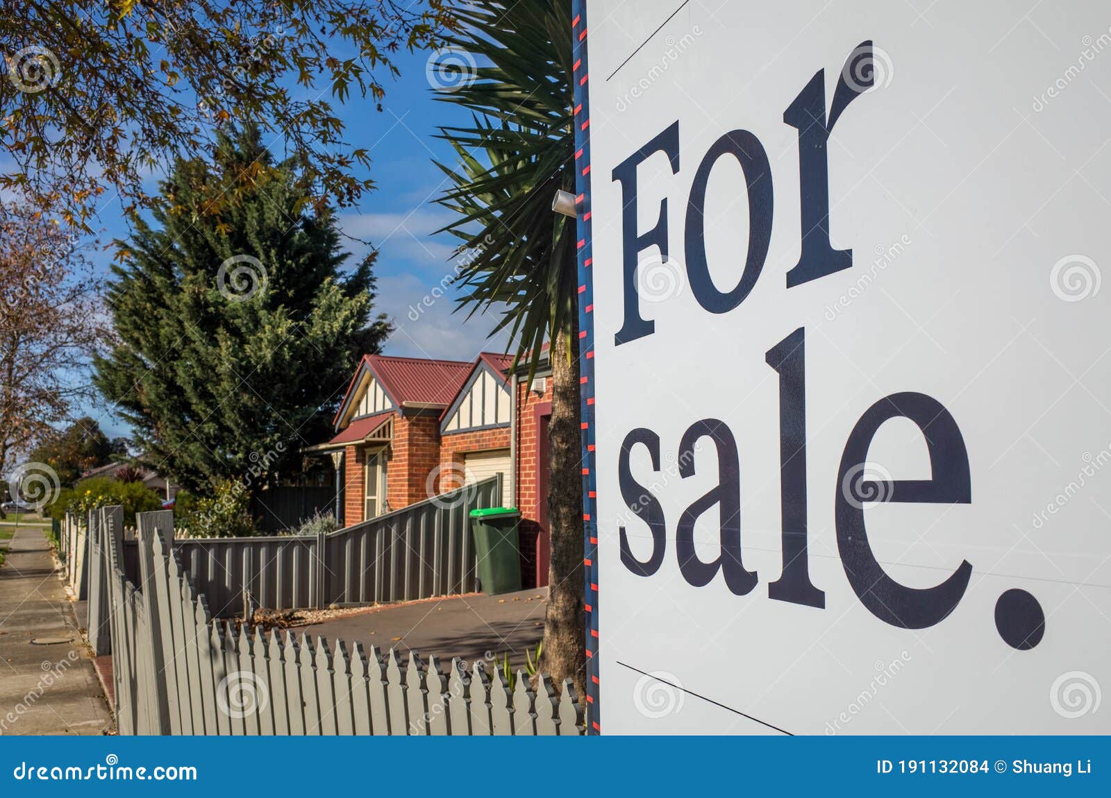 close up of a real estate sign board with text  `for sale` , some suburban houses/australian homes and pedestrian walkway as