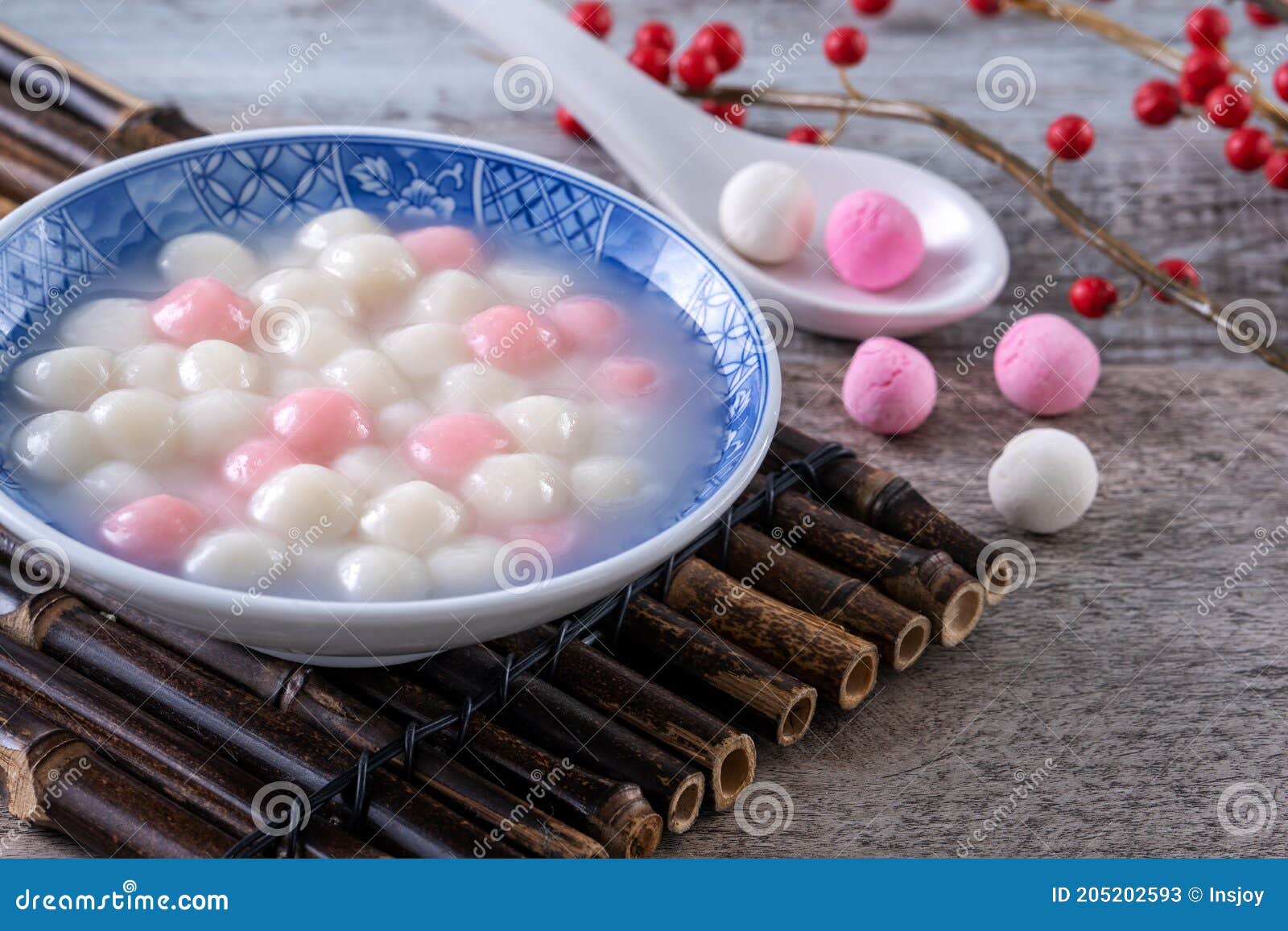 close up of red and white tangyuan in blue bowl on wooden background for winter solstice