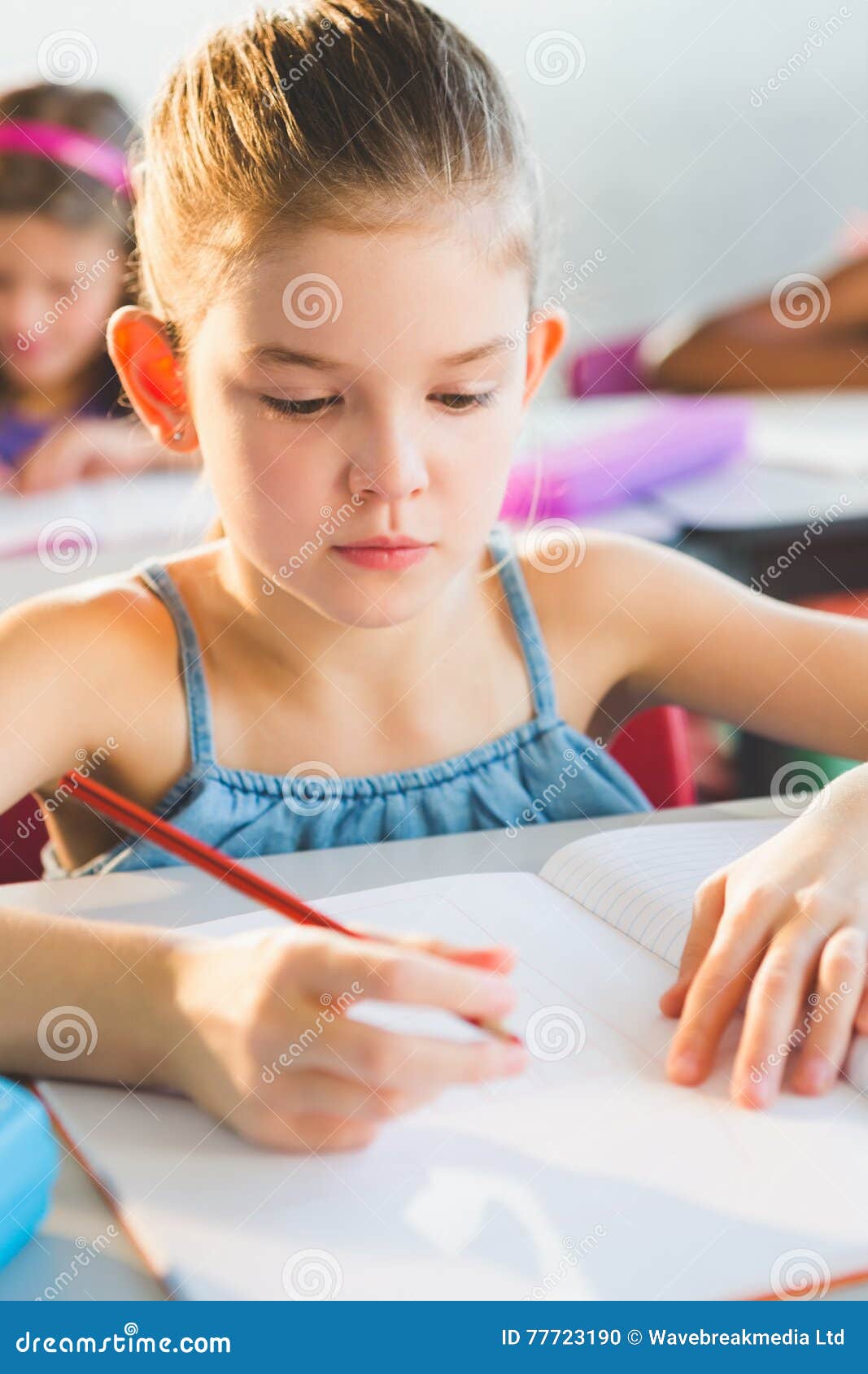 close-up of schoolkid doing homework in classroom