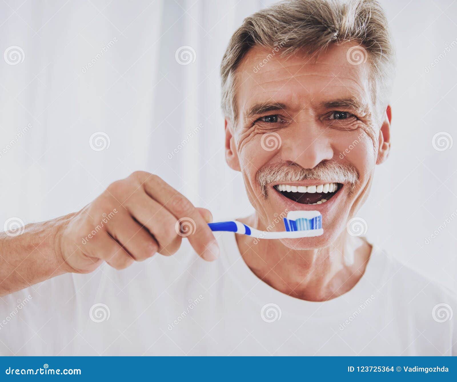 close up. senior man brushing teeth in bathroom.