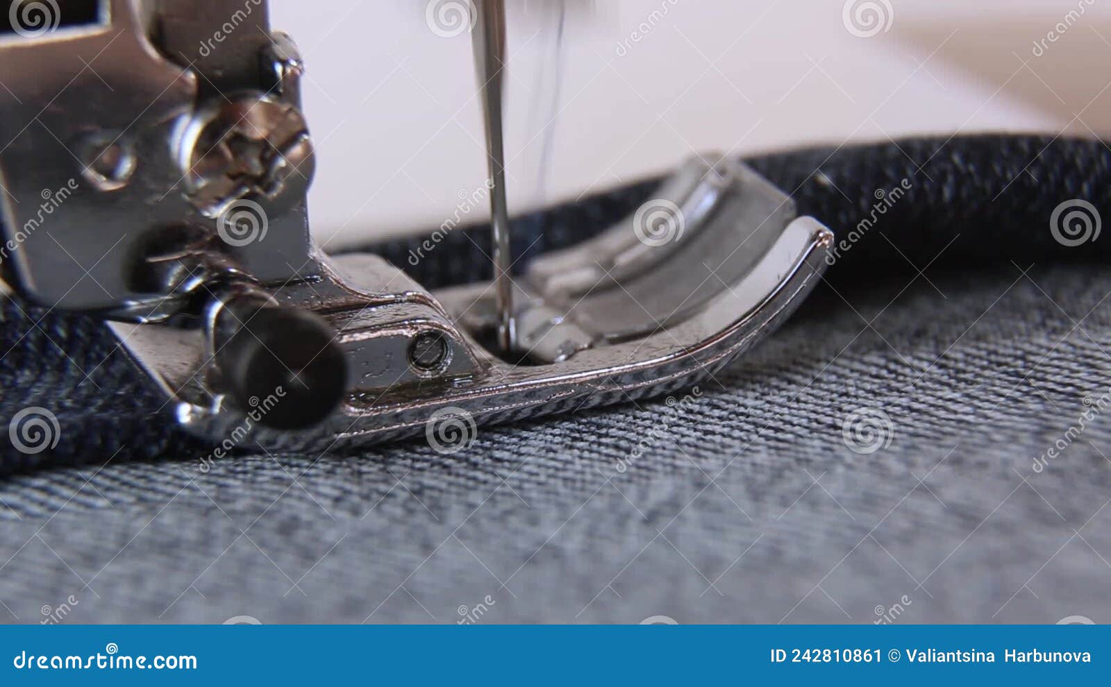 A Closeup Sewing Machine Sews Blue Denim. the Sewing Machine Needle is