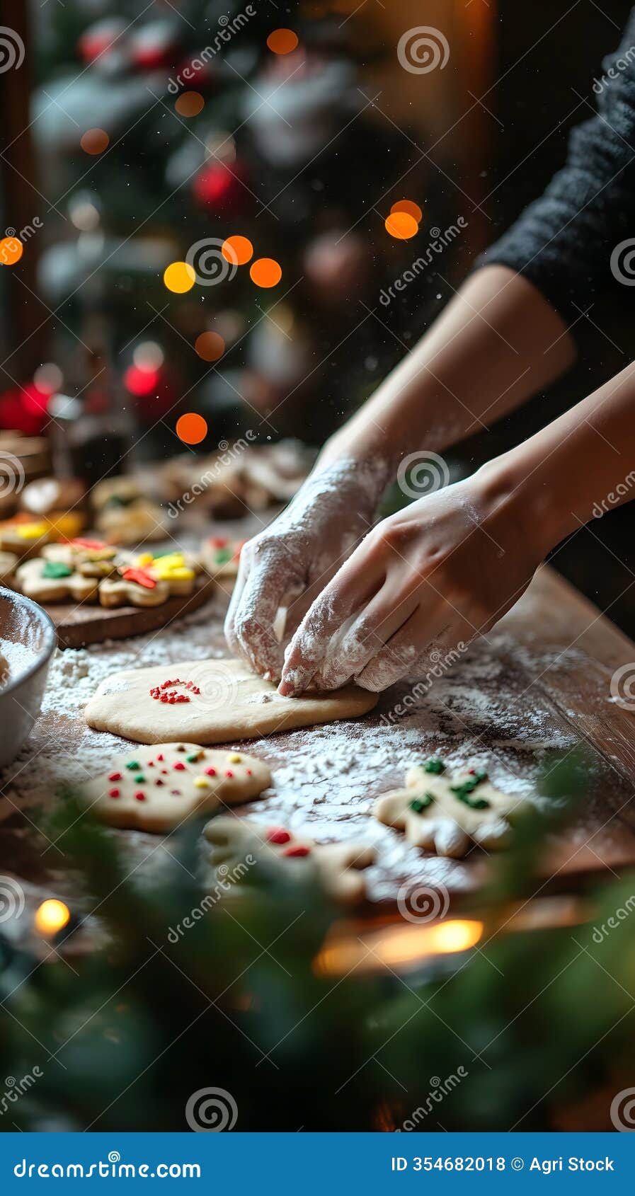 hands decorating christmas cookies with red sprinkles on a floured surface