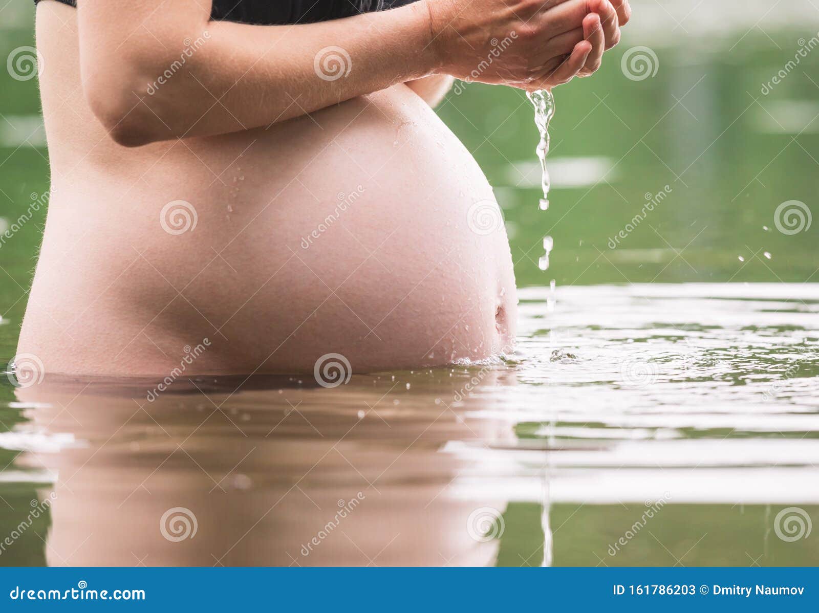 Pregnant Woman Pouring Water on Her Belly Bathing Outdoor Stock