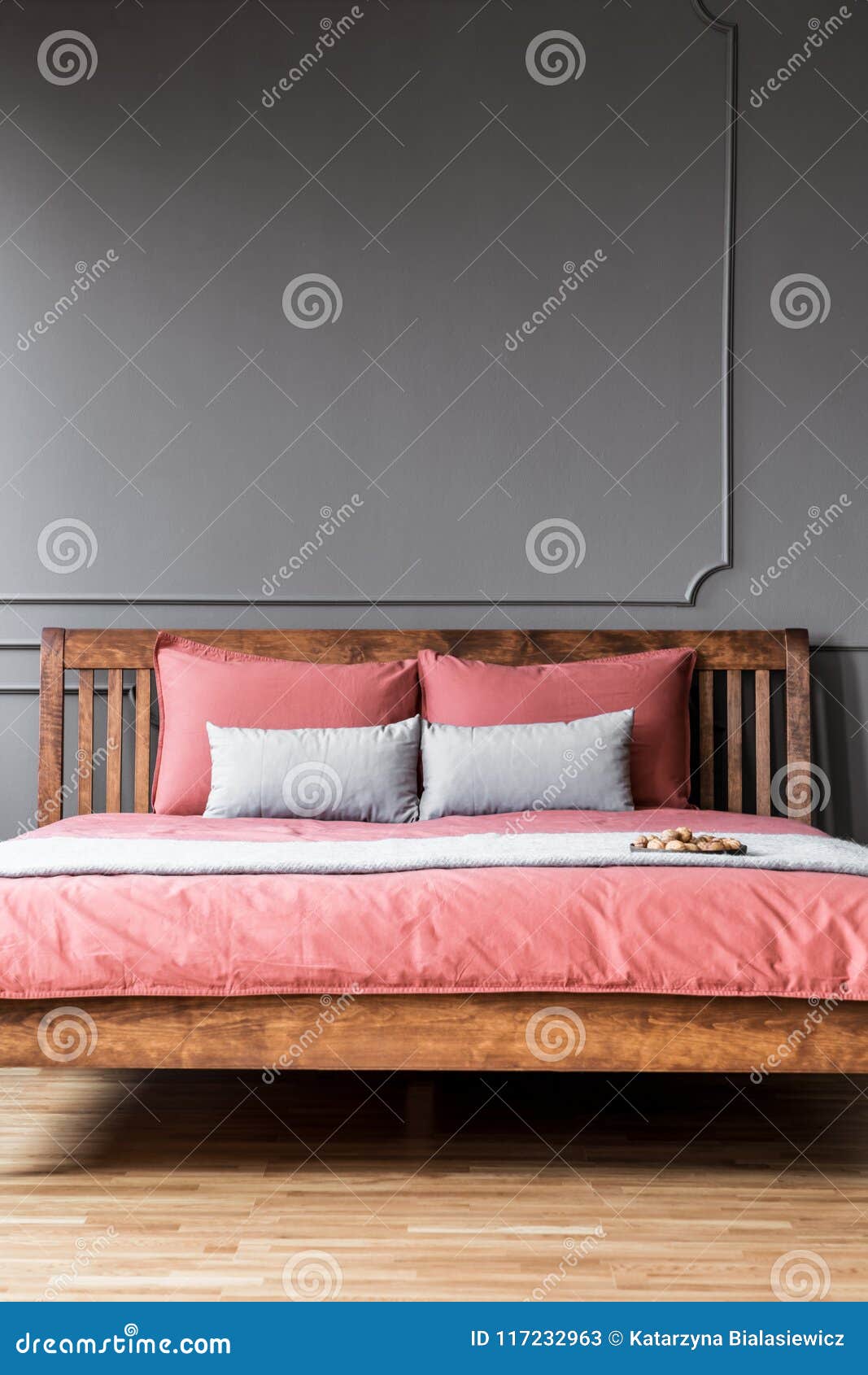 close-up of a simple bed with wooden bedhead and pink sheets in