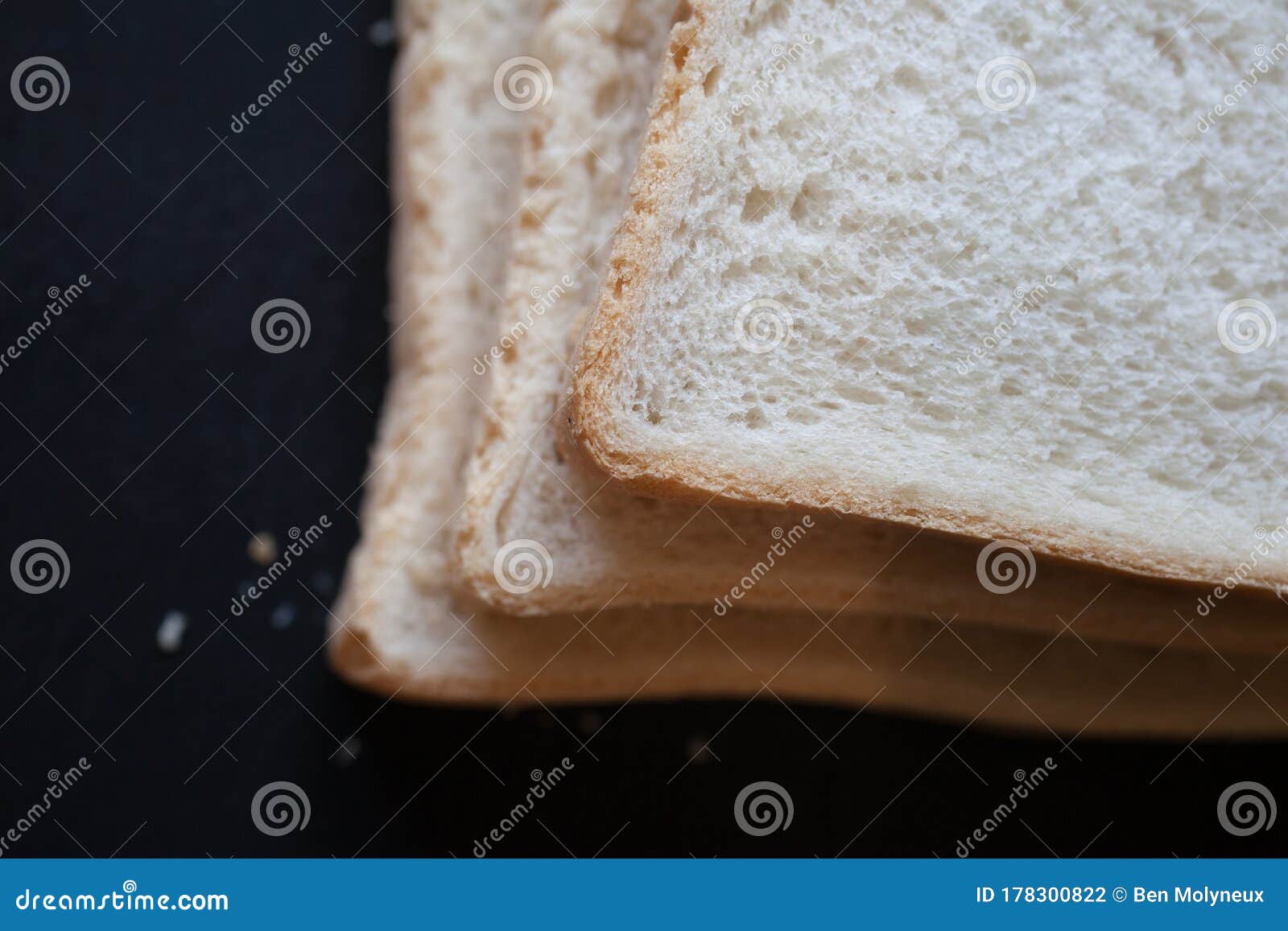 a close up of 3 slices of white bread against a black background