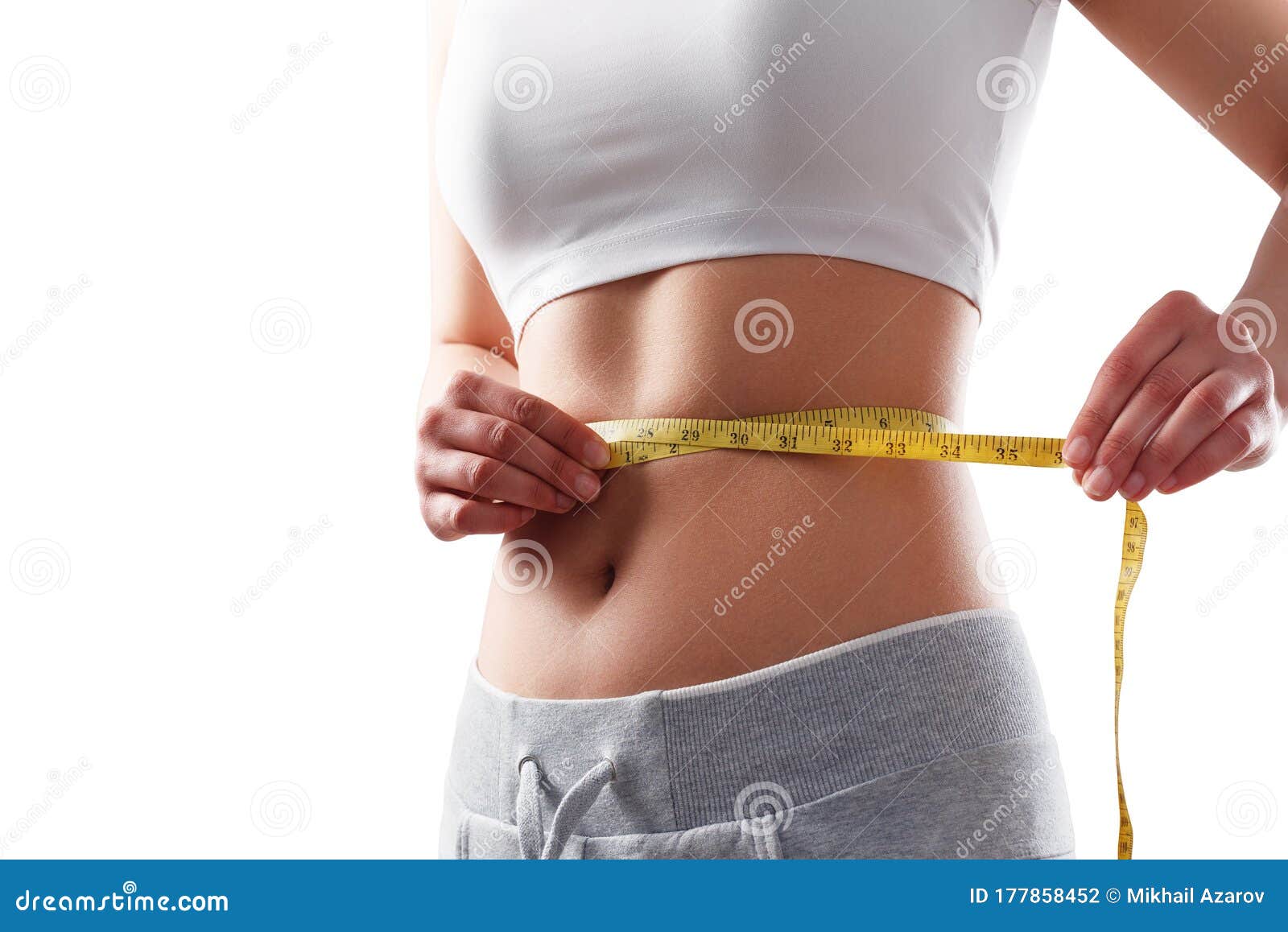 Slim young woman measuring her thin waist with a tape measure, close up  Stock Photo