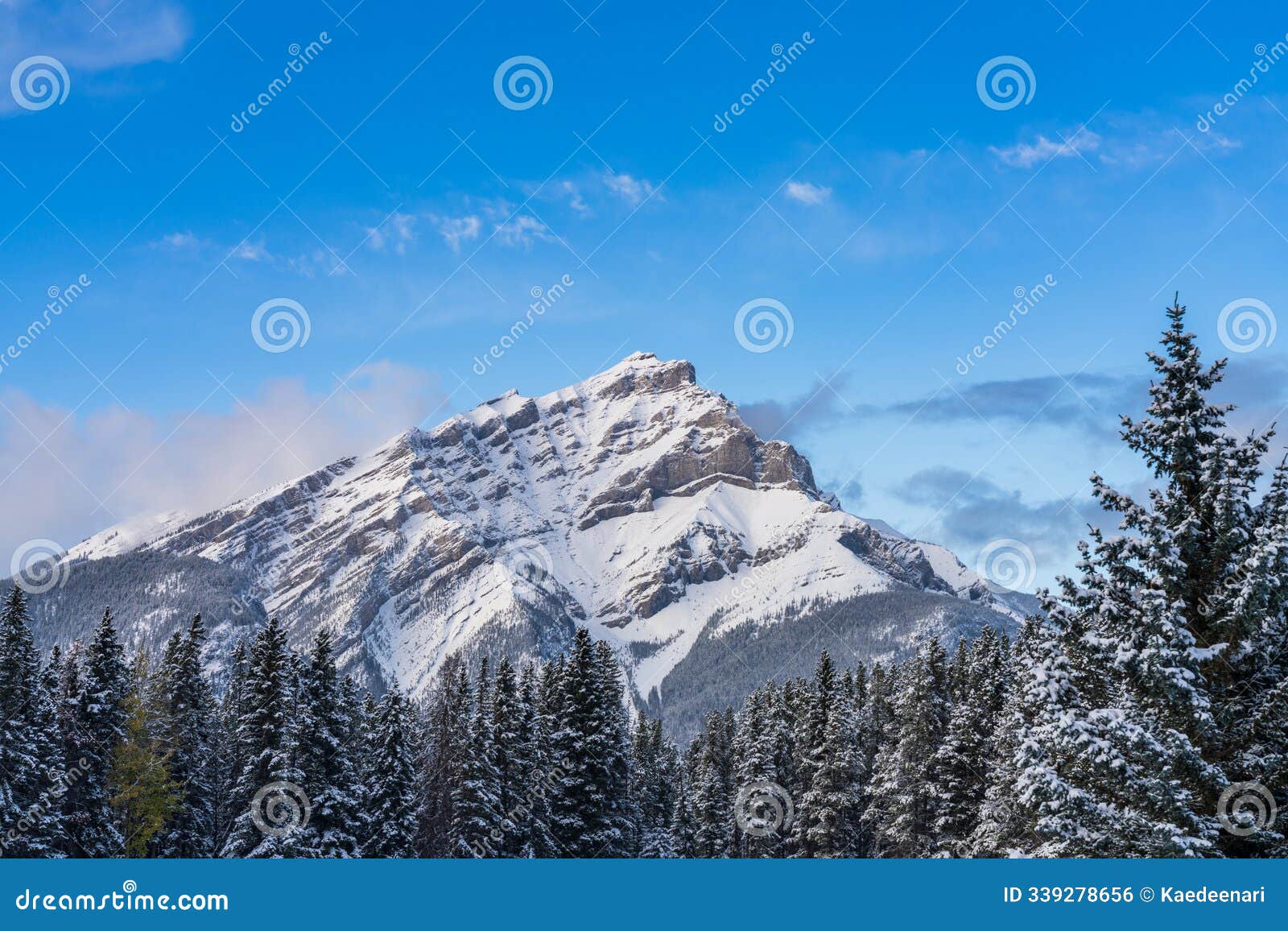 cascade mountain with snowy forest over blue sky and white clouds in winter sunny day. banff national park. canadian rockies.