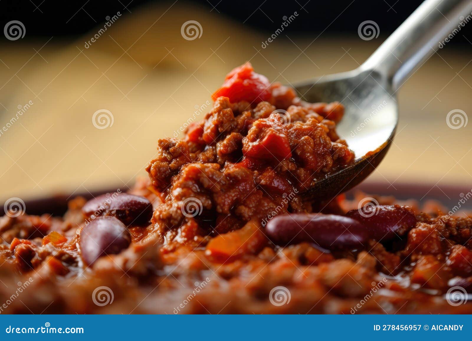 close-up of a spoonful of chili con carne with vibrant red color and texture of ground beef, beans, and tomatoes