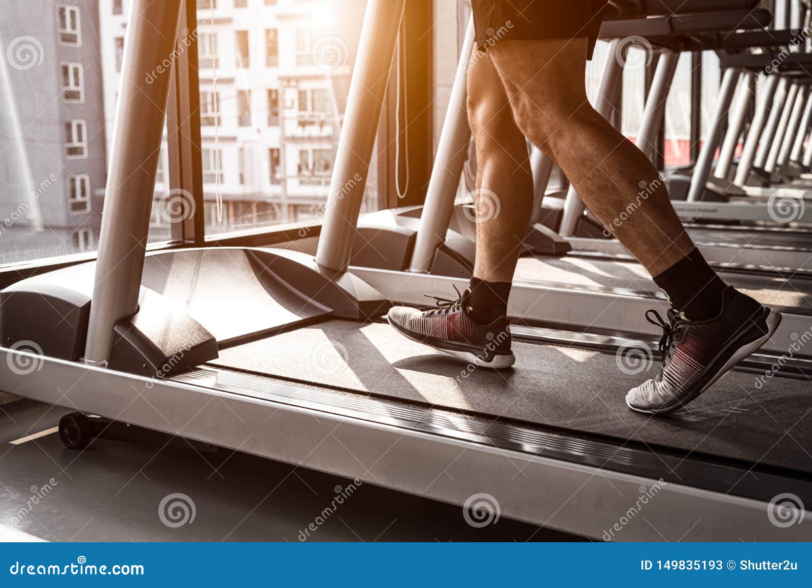 close up of sport man running on treadmill in fitness gym at condominium in urban. people lifestyles and sport activity concept