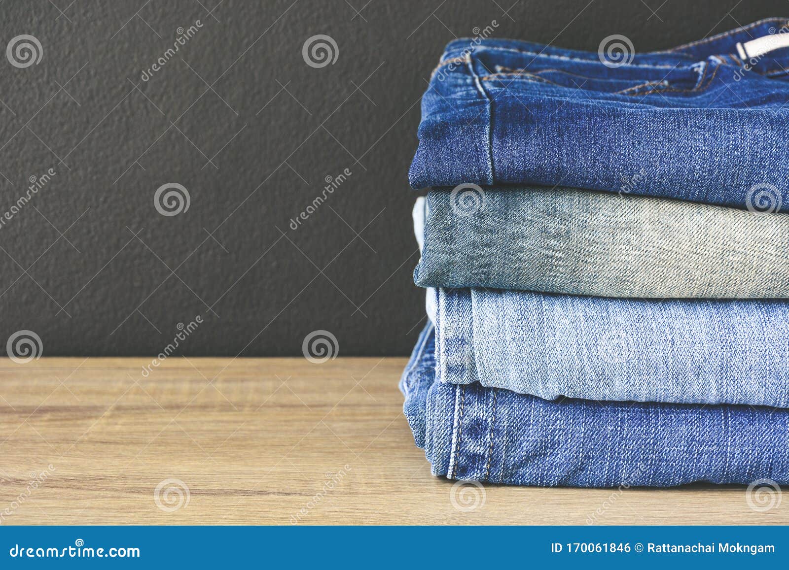 Close Up Stack of Folded Denim Blue Jeans on Wooden Table with Black ...