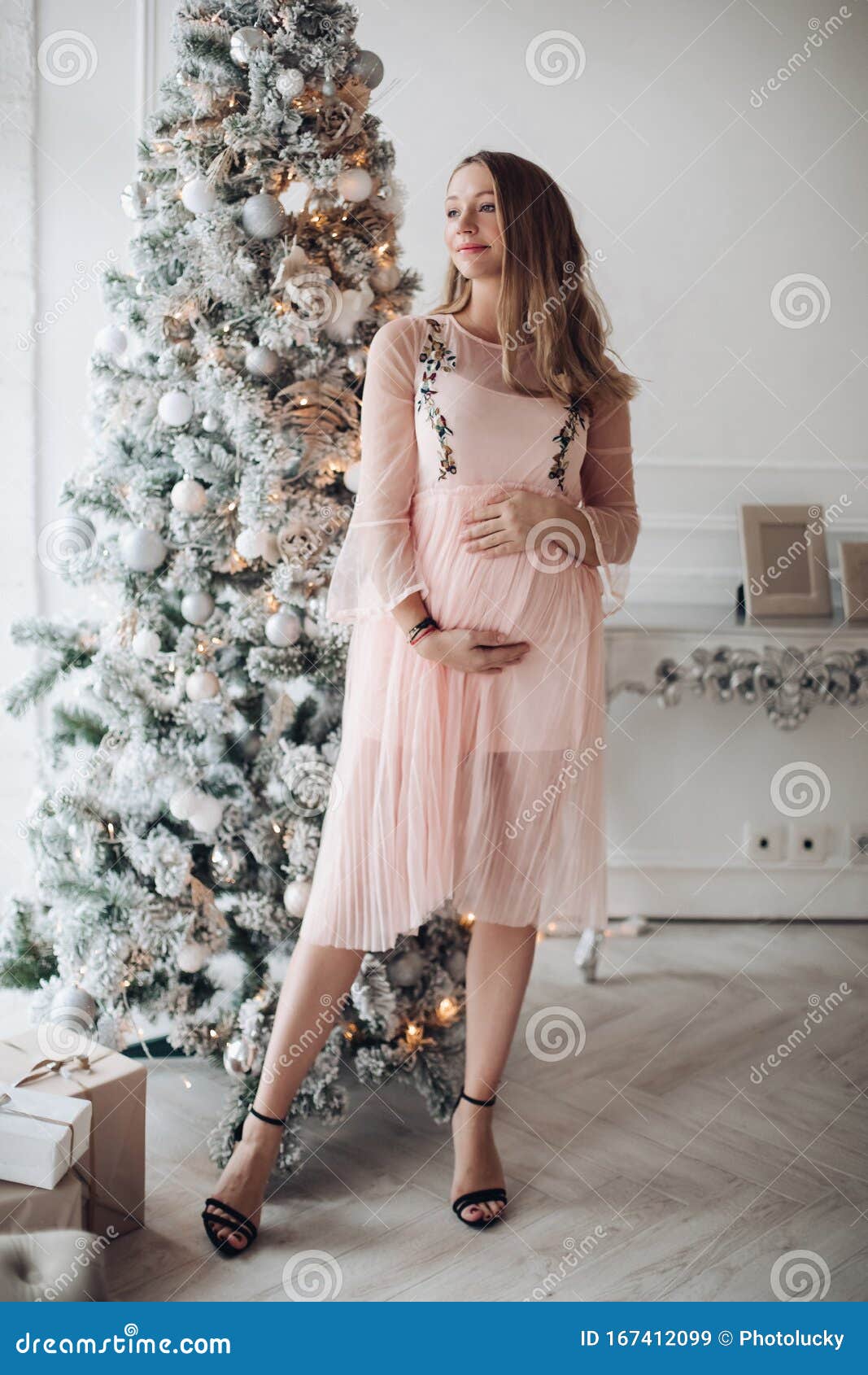close-up tenderness female hand hugging pregnant tummy feeling fondness at christmas tree