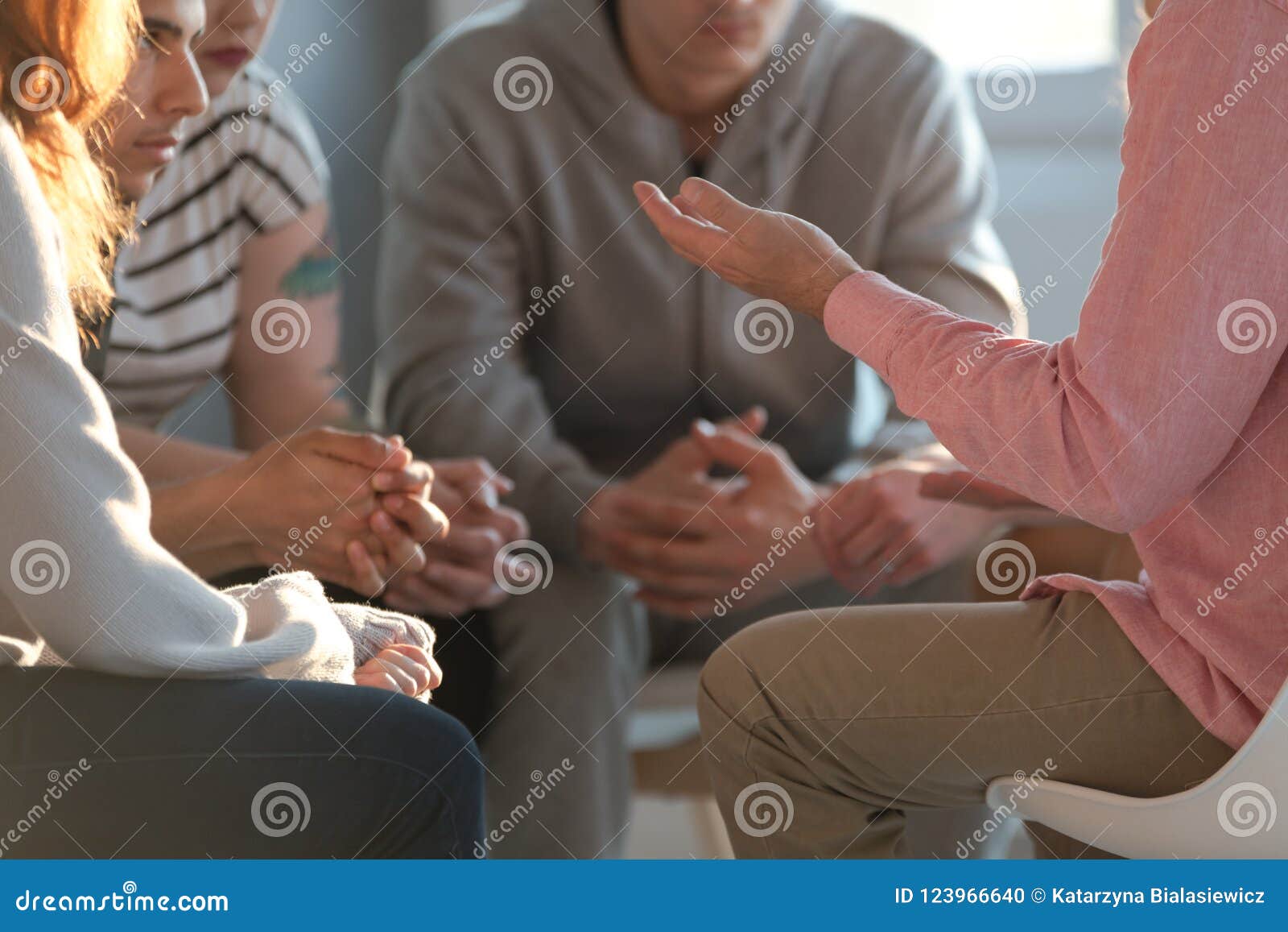 close-up of a therapist gesticulating while talking to a group o