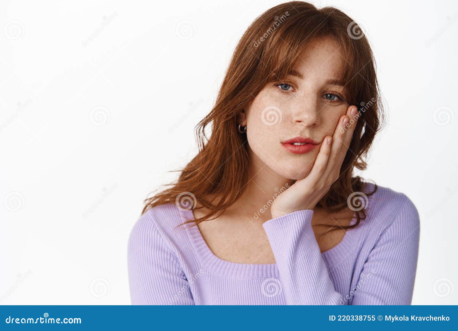 close up of tired young girl with freckles and bangs, lean face on hand, staring reluctant and uninterested, looking