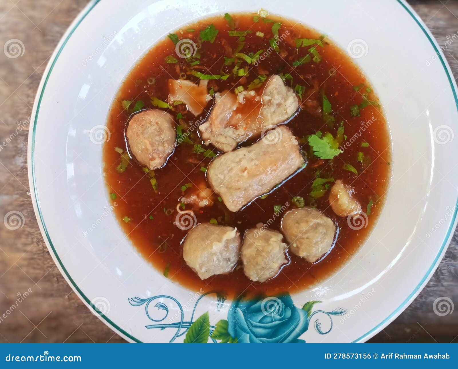 close up of traditional indonesian food called bakso, which is a meatball soup, on white plate