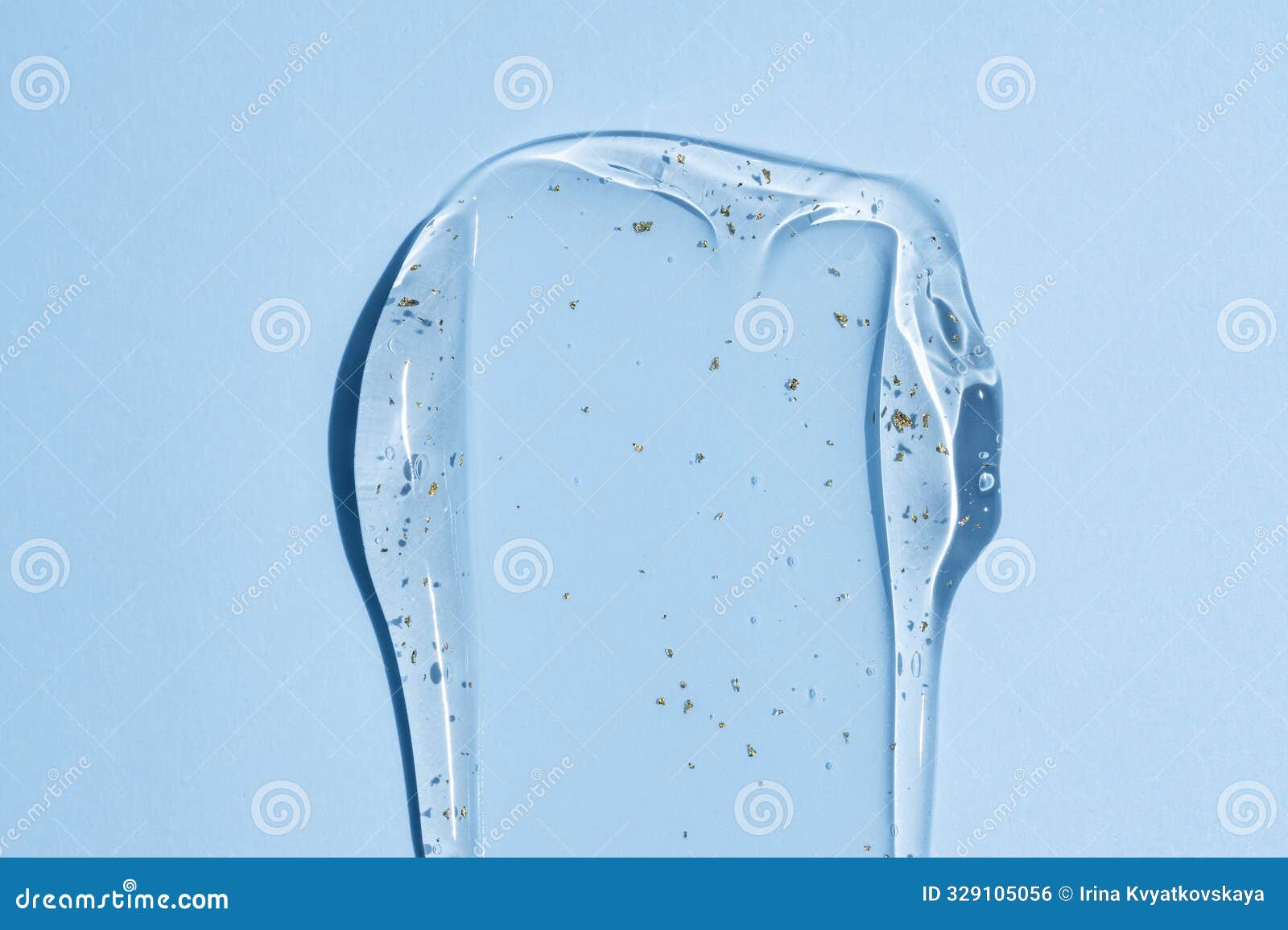 close-up, transparent 24k gold serum drop smear on blue background, showcasing squeezed clear cosmetic cream gel texture with