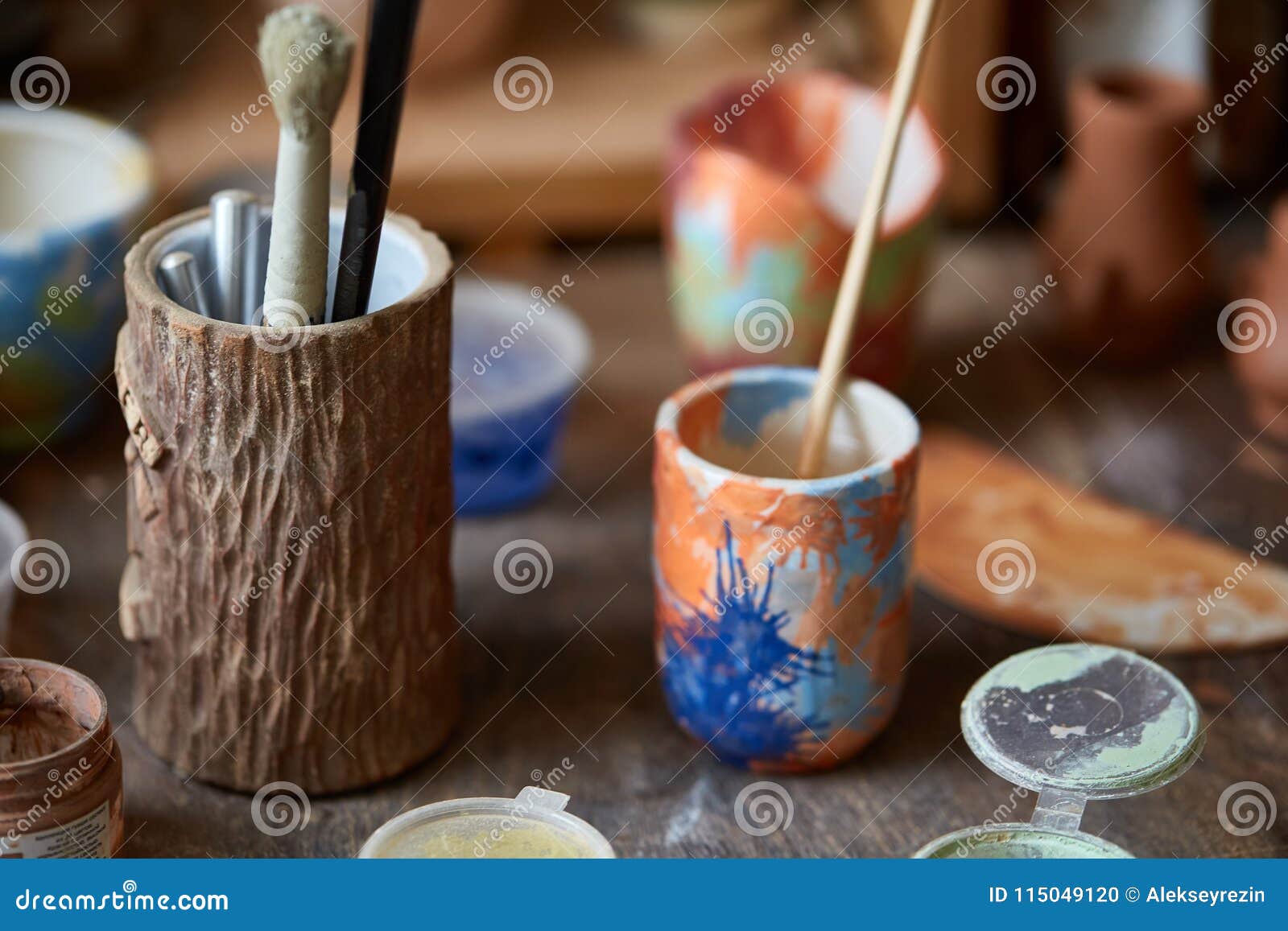 Closeup of Various Paint Mugs and Brushes in Holder on Worktop
