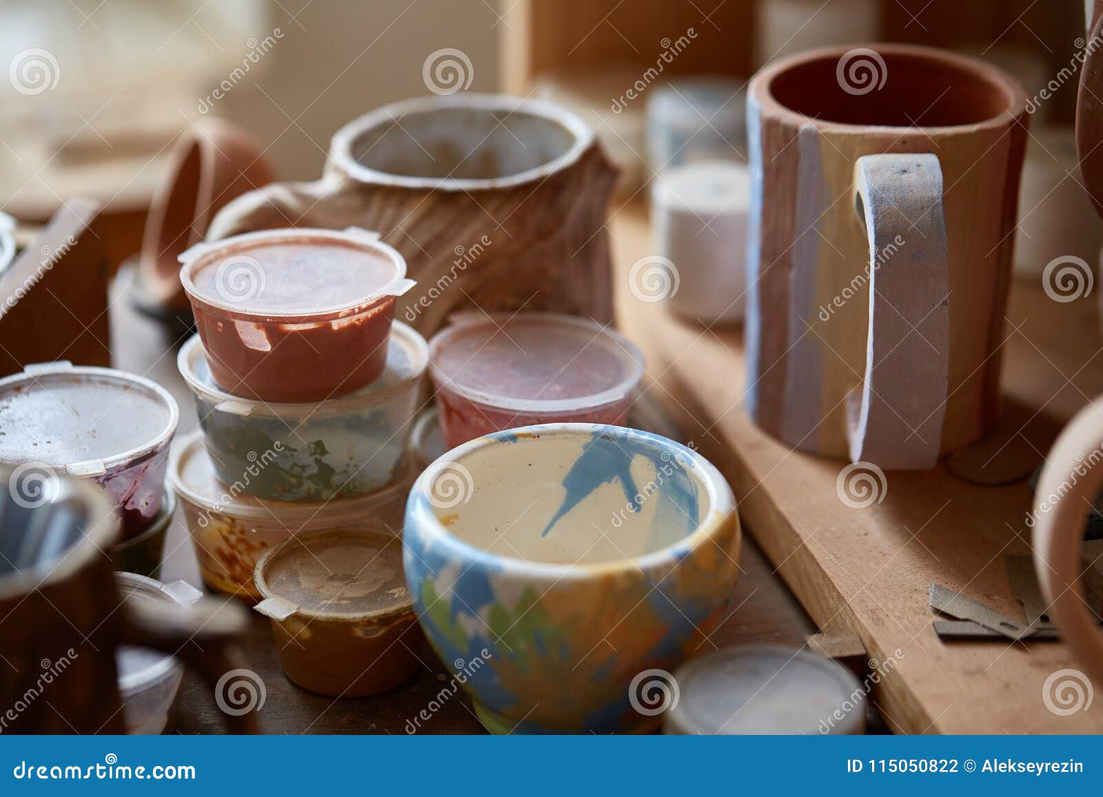 Closeup of Various Paint Mugs and Brushes in Holder on Worktop