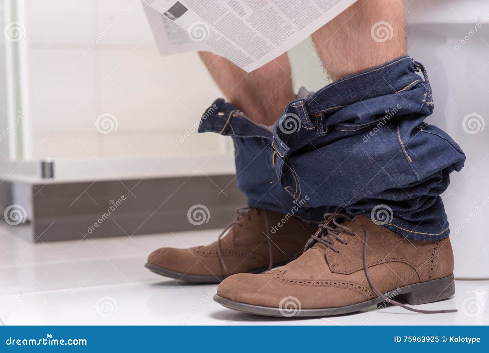 Male Reading Newspaper While Sitting On The Toilet Seat 