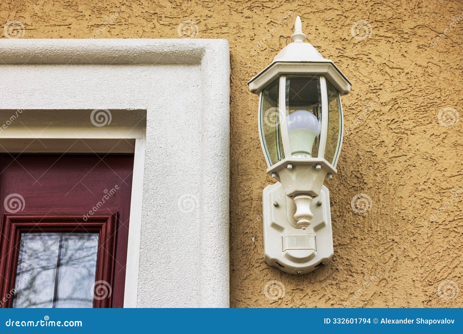 close up view of plaster wall with a built-in ornate lantern, yellow-orange putz finish, and concrete door frame.