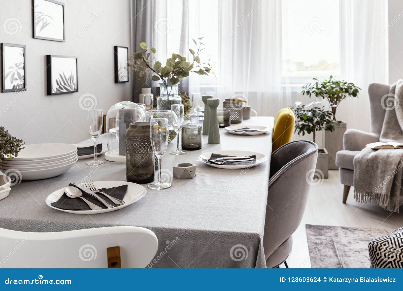 well-laid table with plates and glasses in a grey dining room interior. real photo